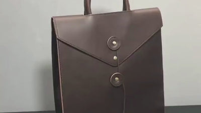 シンプルなデザインのPUレザー製 バックパック_男女兼用_A。フロントのボタン装飾が特徴的なユニセックスバッグ。